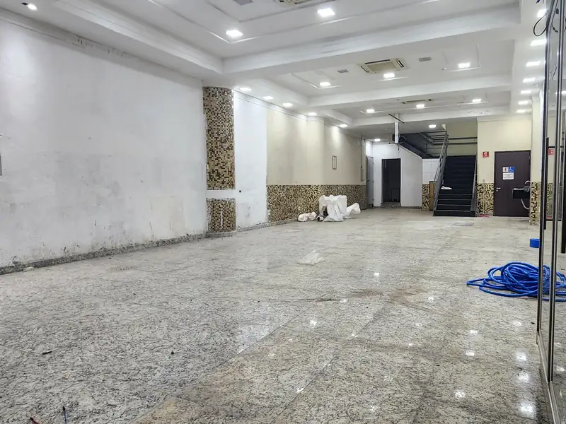 Salão comprido com pé-direito alto e iluminação embutida